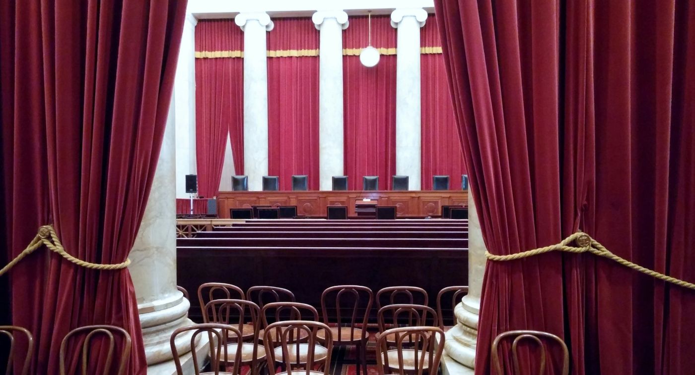 The United States Supreme Court courtroom, its nine-seat bench framed by red drapes and marble columns