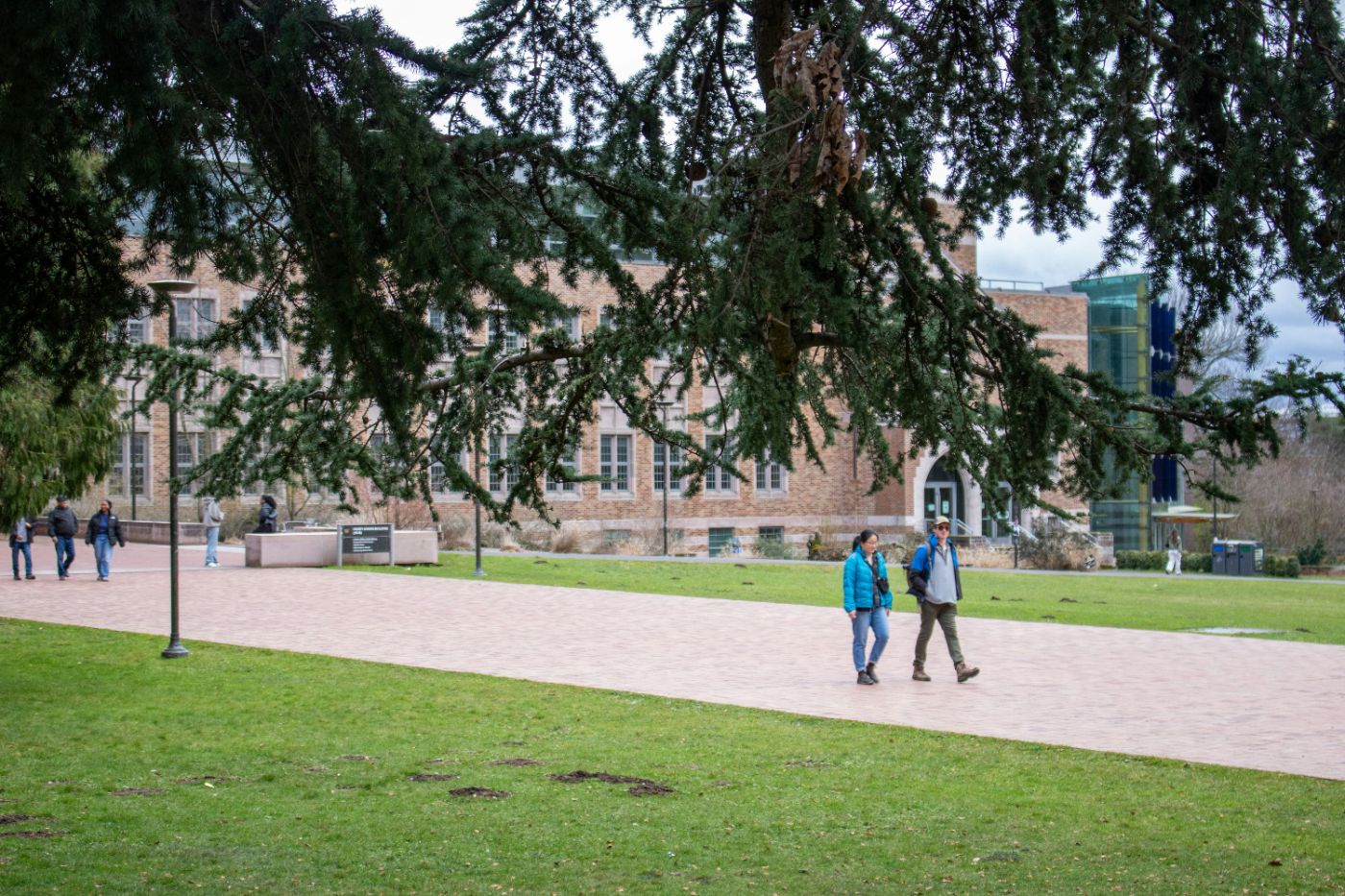 Students walking past a brick college building on a tree-lined campus, illustrating paying for college after divorce