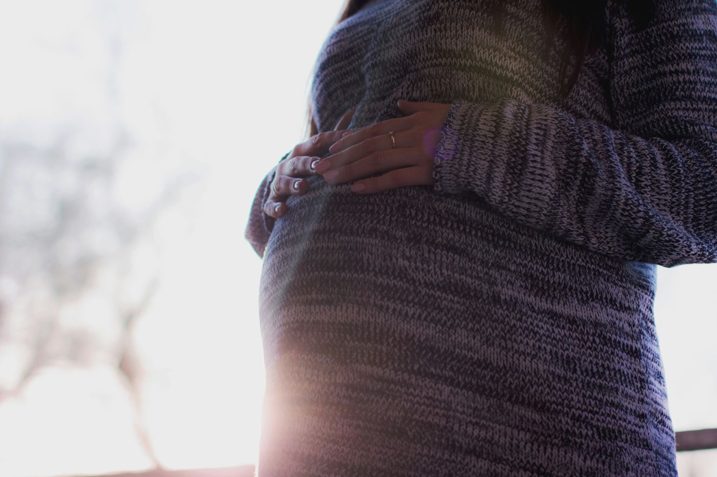An expectant mother rests her hands on her belly in daylight, a reminder that child support from conception in South Carolina begins before birth