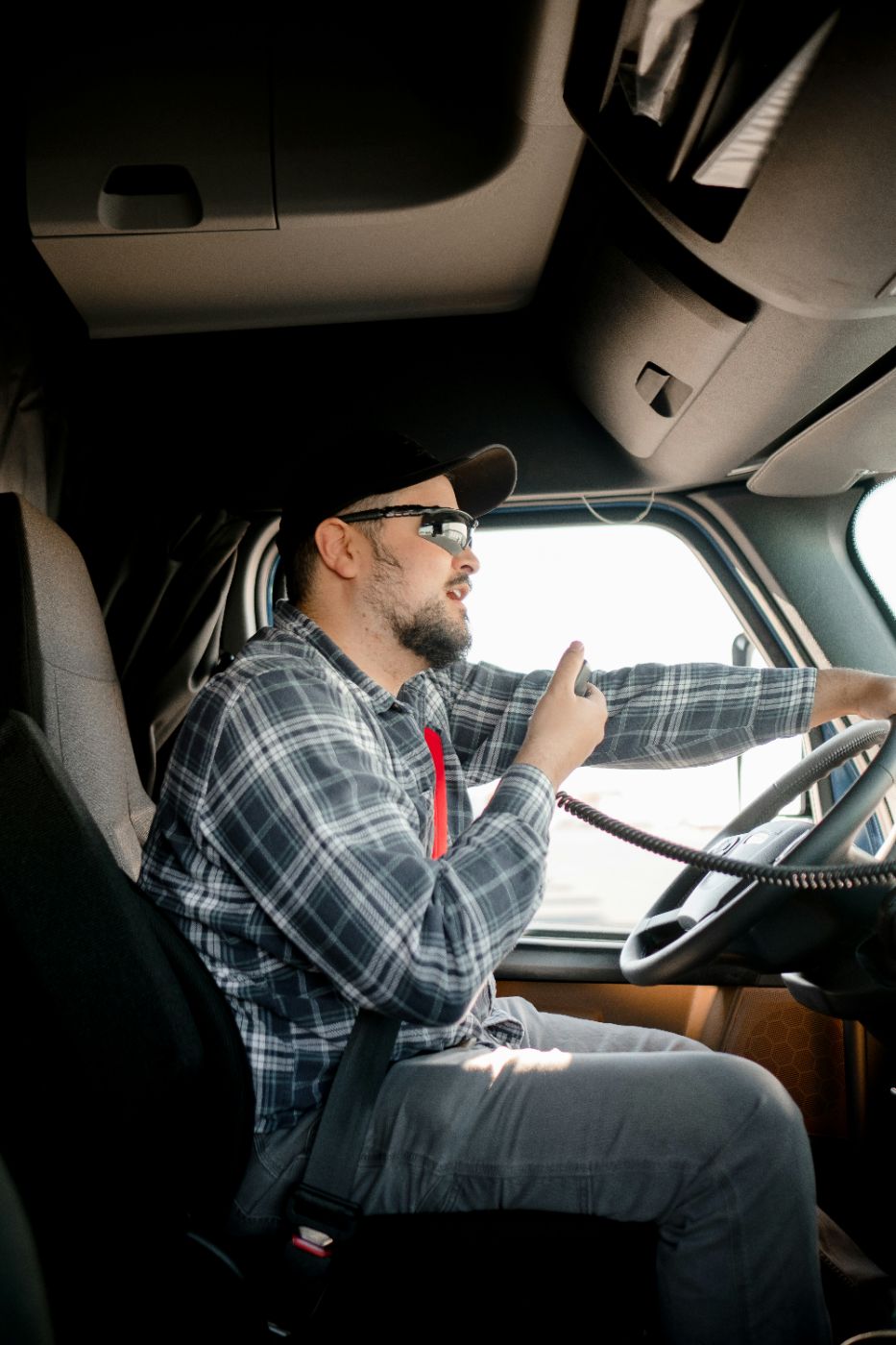 A truck driver at the wheel of a tractor-trailer cab, illustrating electronic logbooks in trucking accidents.