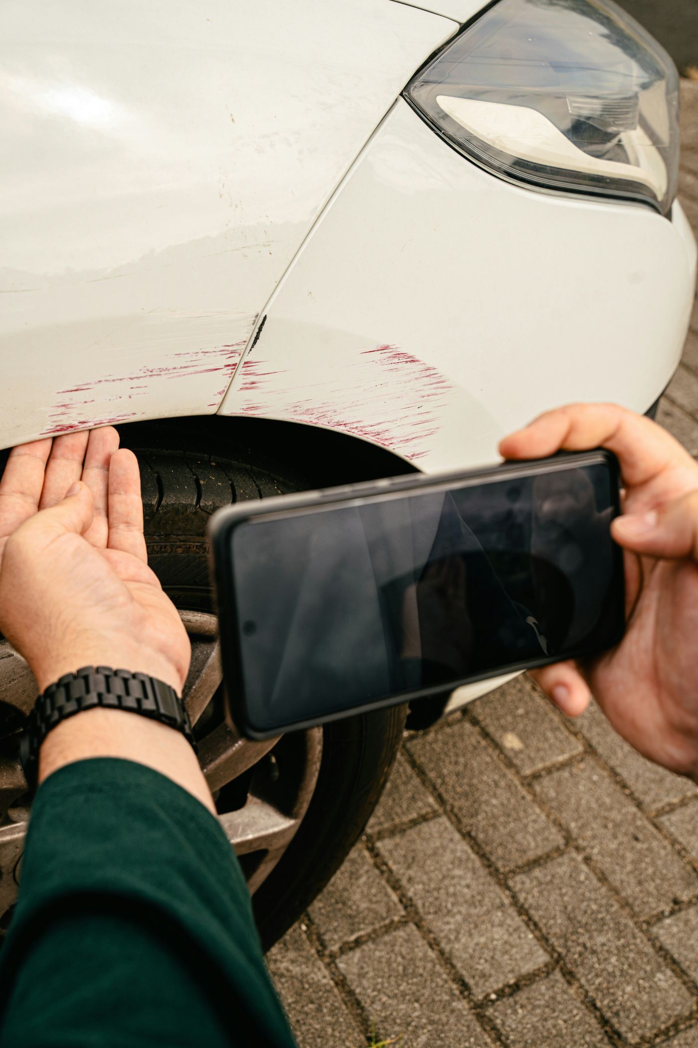 A driver photographing vehicle damage at a roadside, showing what to document after a car accident.