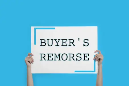 holding up a sign that says 'Buyer's Remorse'
