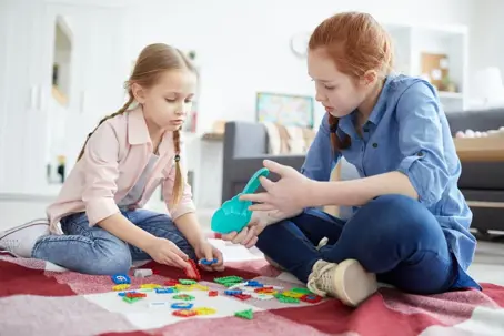 Older sister playing with her younger sister with toys on the floor
