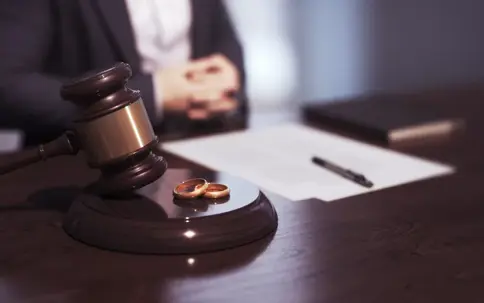 Wedding rings next to a gavel with documents on a desk