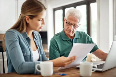 Adult daughter going over forms with eldery father